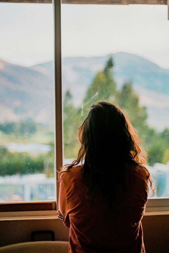 Silhouette of a woman looking out a window at a scenic mountain view in Cajamarca, Peru.