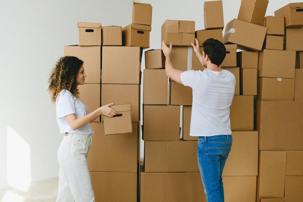 A young couple collaborates to organize and unpack moving boxes in their new home.
